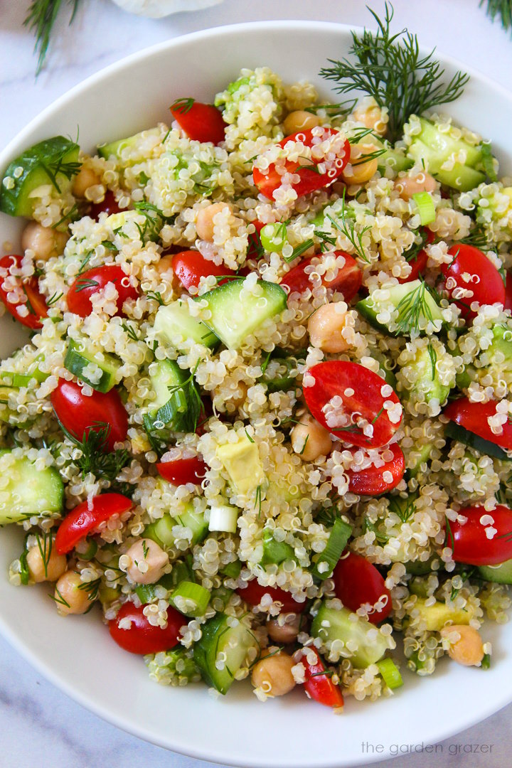 Close up view of quinoa chickpea salad with dill in a white serving bowl