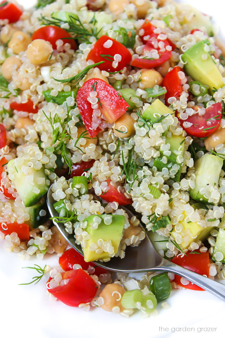 Lemon quinoa salad with avocado and dill on a white plate with serving spoon