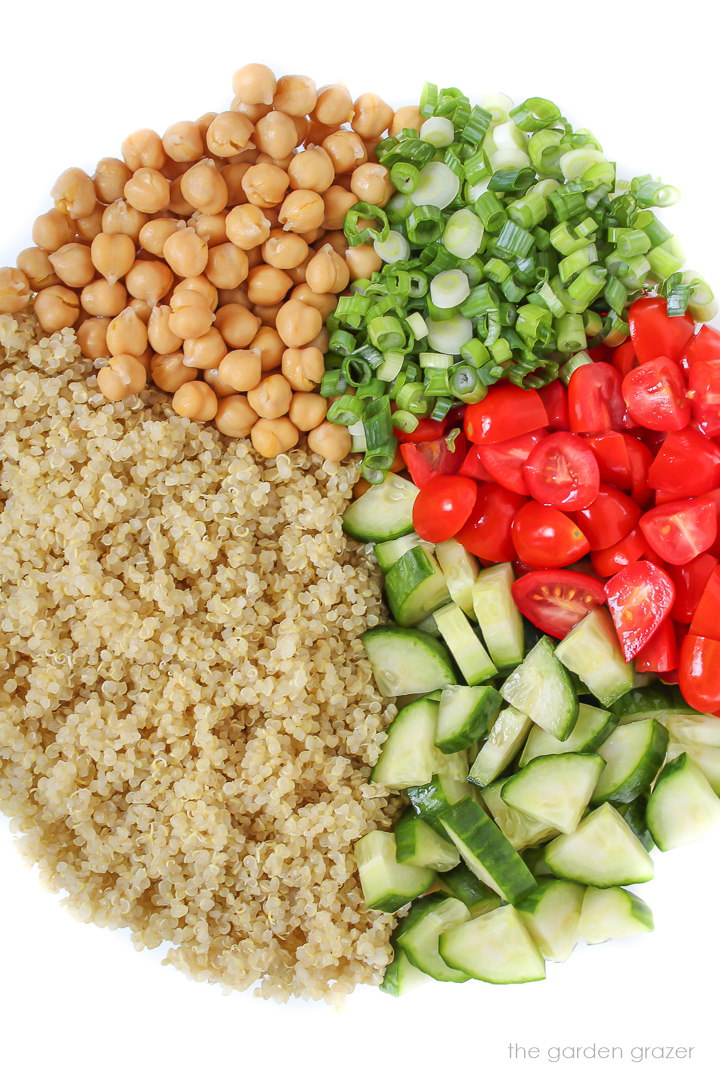 Cooked quinoa, garbanzo beans, diced cucumber, and tomato in a bowl