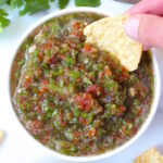 A tortilla chip dipping into a bowl of fresh garden salsa