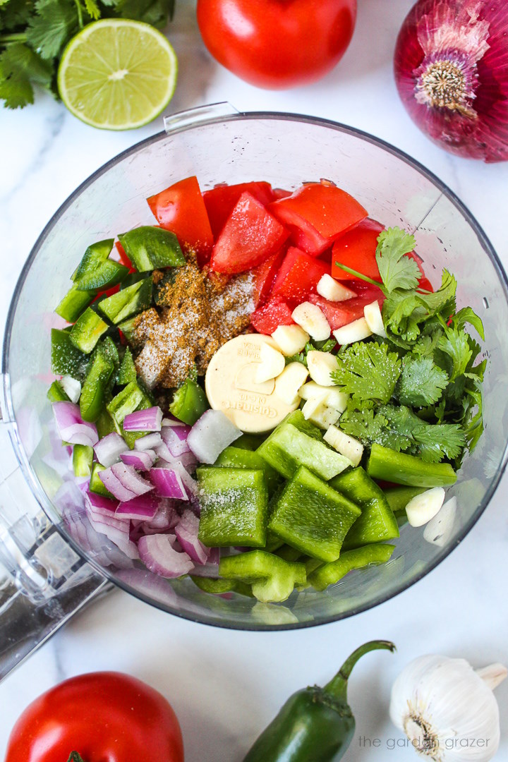 Overhead view of preparing fresh garden salsa ingredients in a food processor before blending