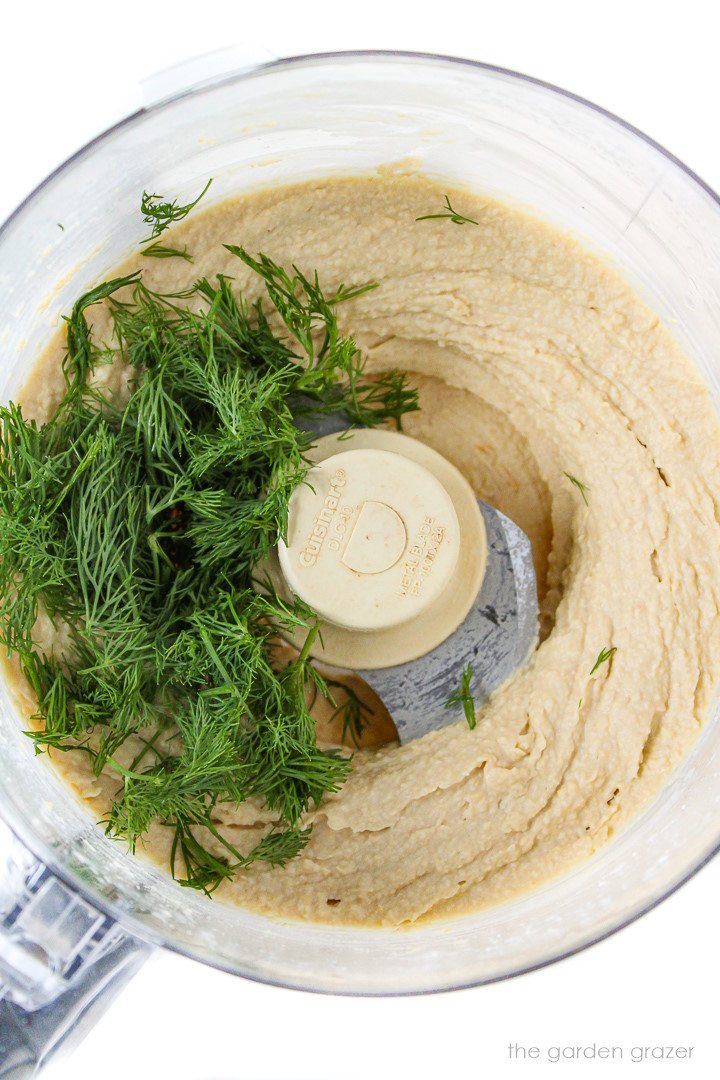 Fresh dill in a food processor with blended hummus