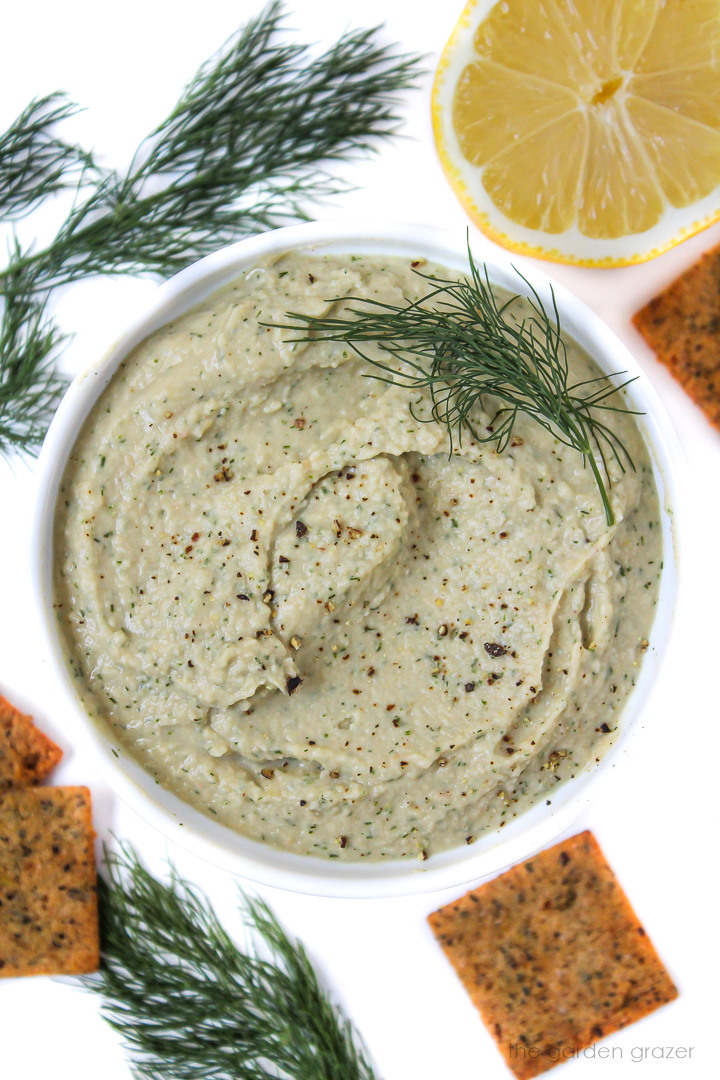 White bowl of lemon dill hummus with fresh dill garnish