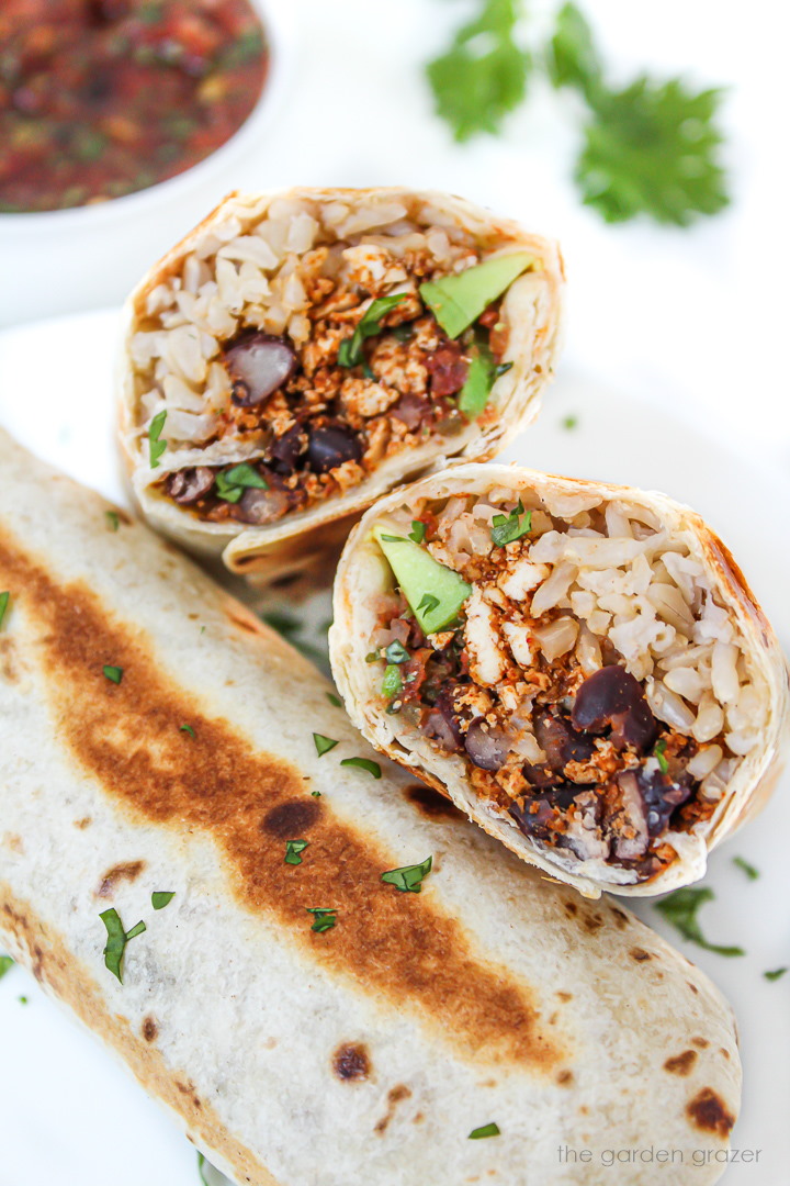 Southwestern tofu burrito cut in half on a white plate