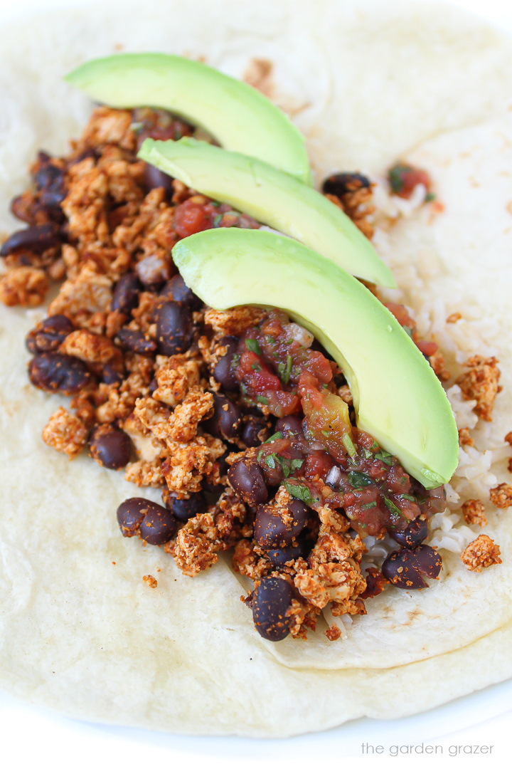 Open-faced burrito with tofu, black beans, salsa, and avocado on a flat tortilla