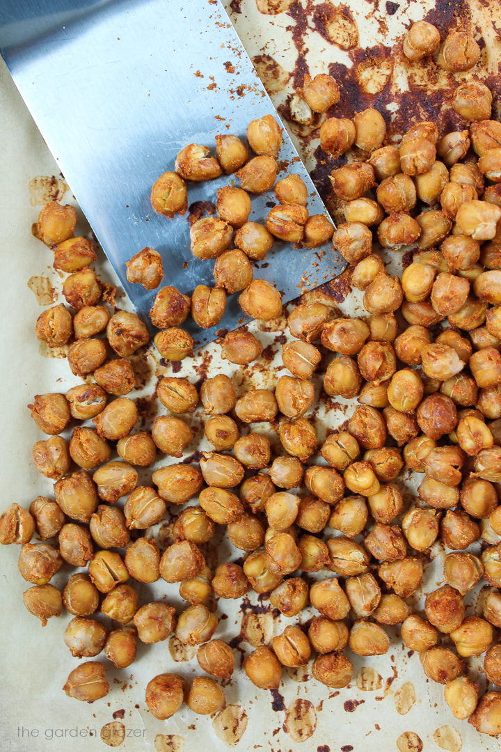 Smoky roasted chickpeas on a baking pan with metal spatula
