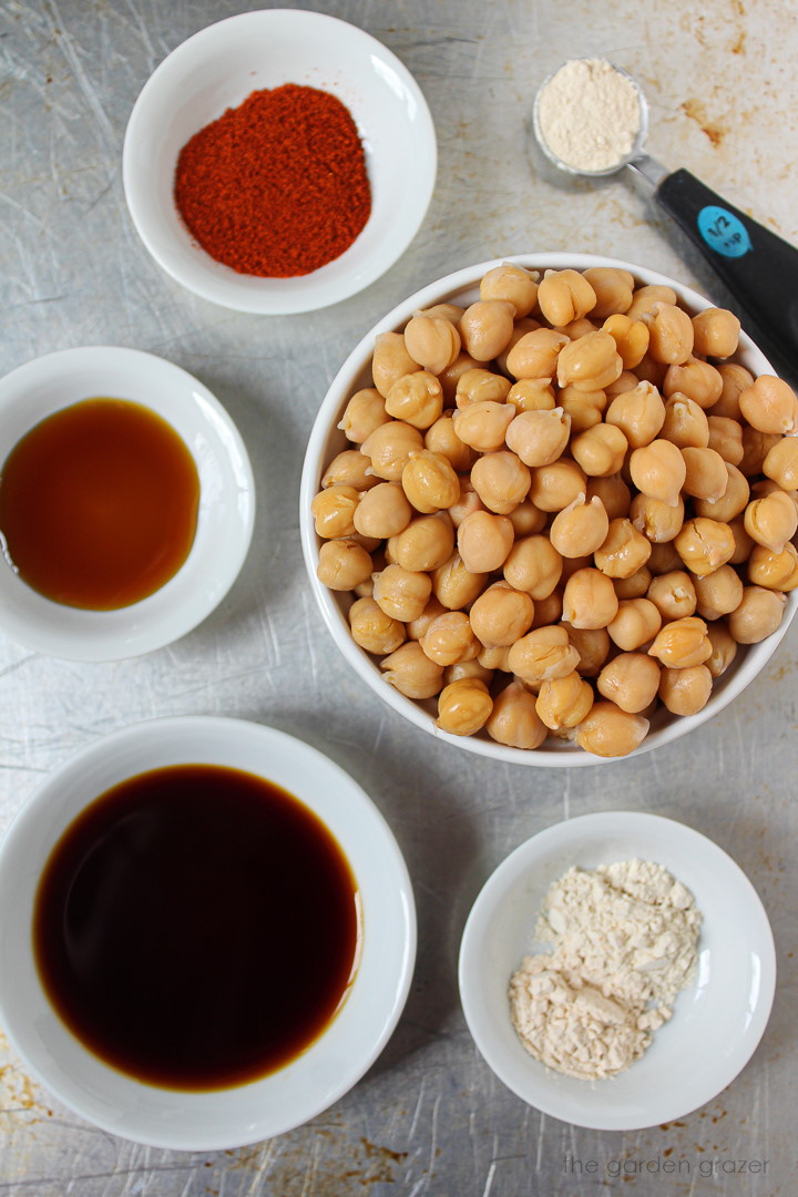 Garbanzo beans, tamari, and spices laid out on a table in bowls