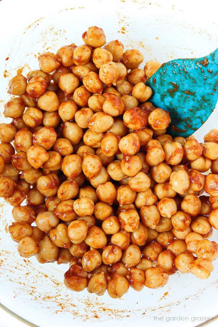 Garbanzo beans mixed with a spice blend in a glass bowl