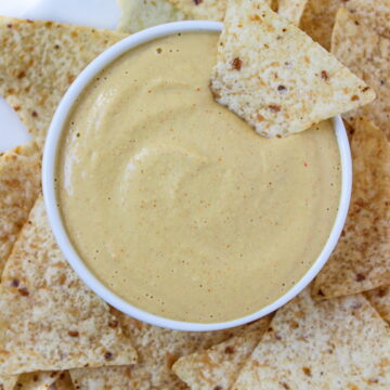 Cashew queso in a white bowl surrounded by tortilla chips