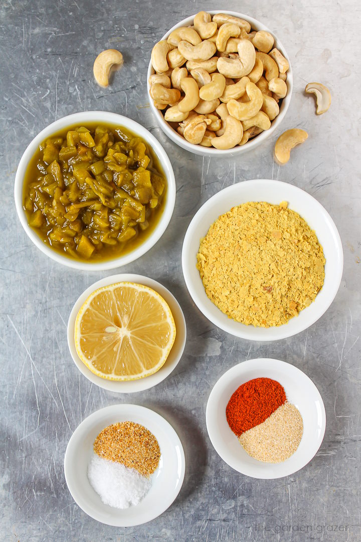 Raw cashews, nutritional yeast, green chiles, lemon, and spice ingredients laid out on a metal tray