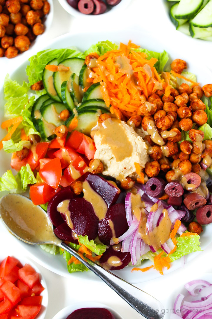 Close up view of roasted chickpea salad with hummus in a white serving bowl