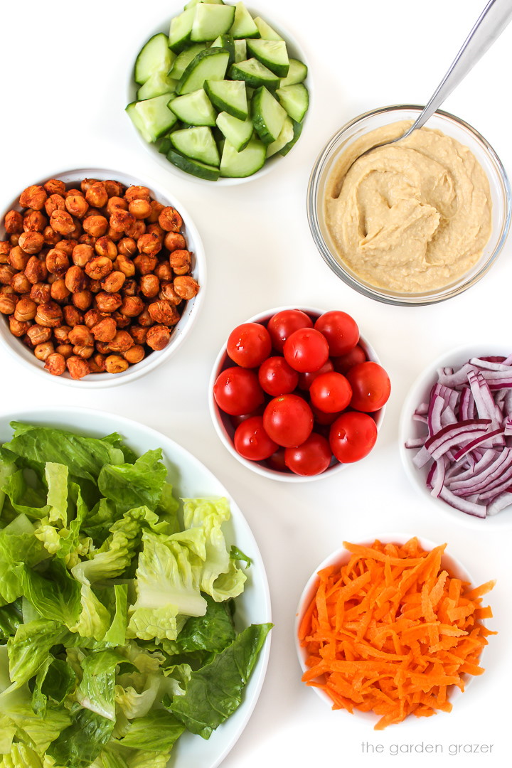 Separate salad ingredients laid out in bowls on a white table