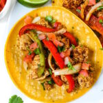 Close up view of tofu fajitas served on a white plate with cilantro and salsa