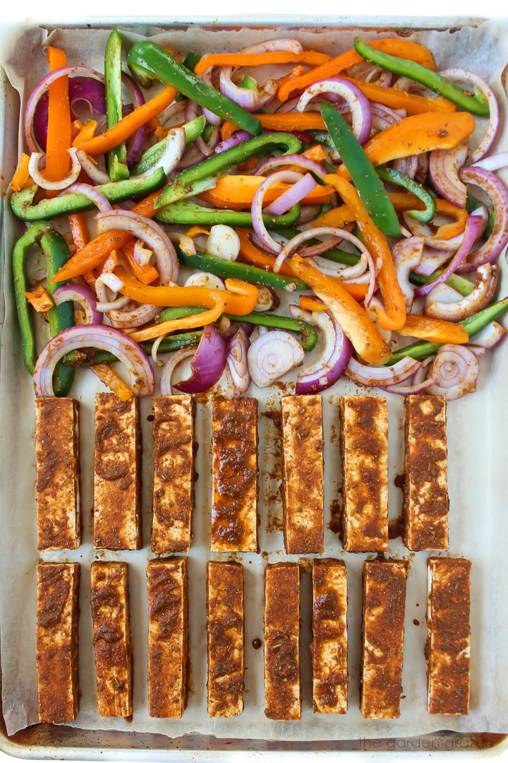 A sheet pan with taco-seasoned tofu and sliced bell peppers and onions