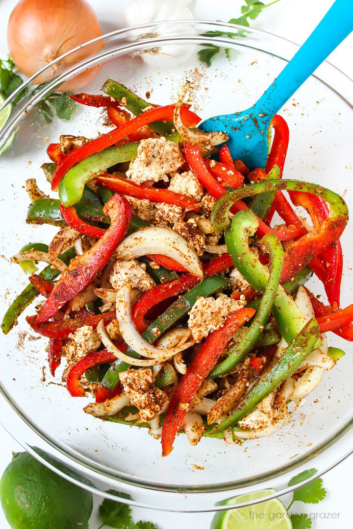 Preparing sliced bell peppers and onions in a bowl with seasoning