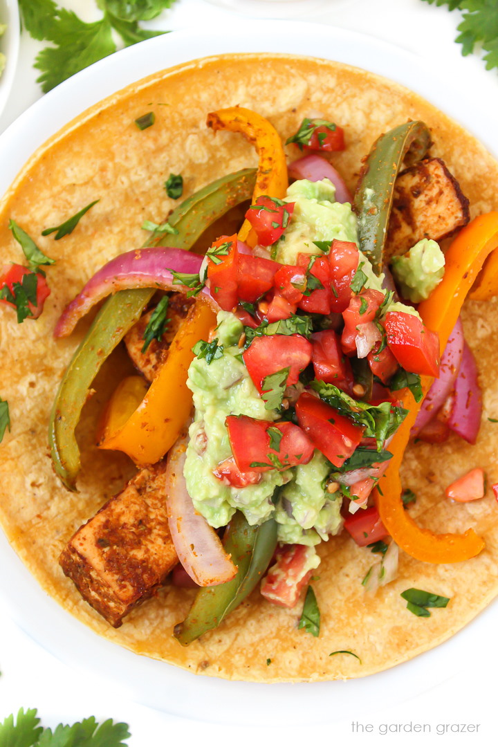 Open-faced vegan tofu fajitas on a corn tortilla with salsa and guacamole