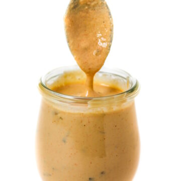 Spoon dipping into a small glass jar of vegan big mac sauce