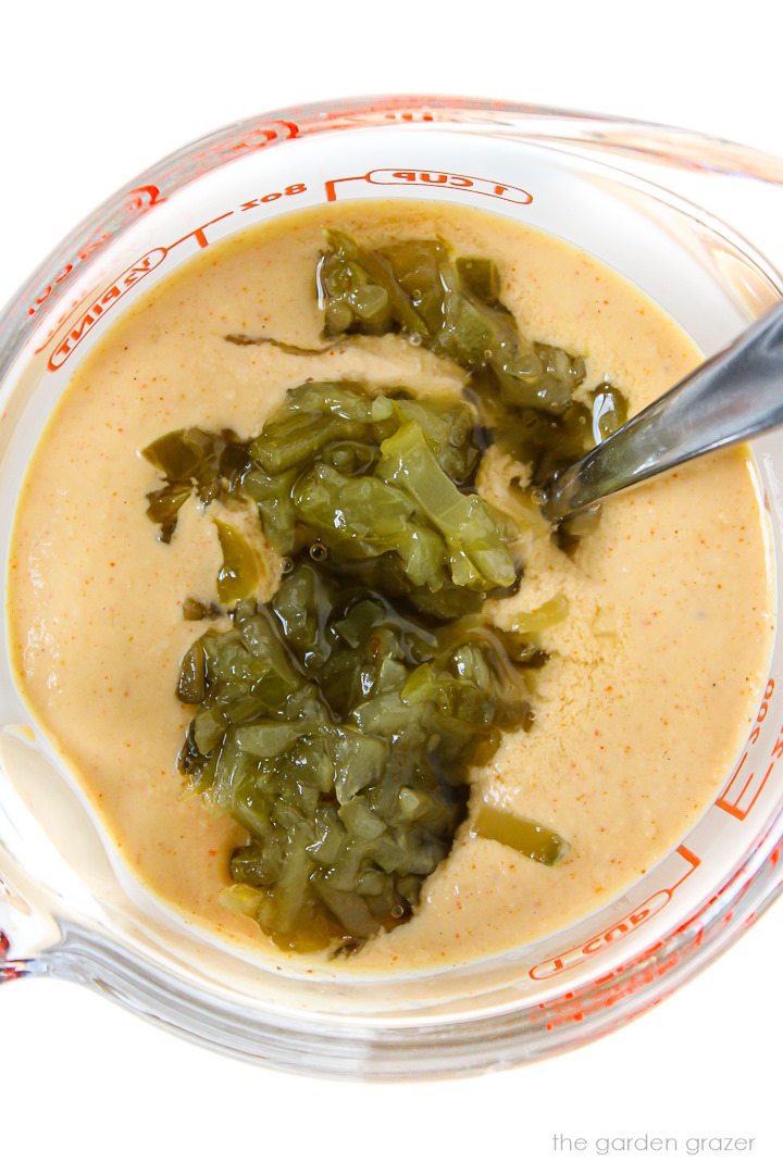 Preparing vegan big mac burger sauce in a glass cup with spoon