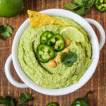 Cilantro jalapeno hummus in a white bowl on a wooden table