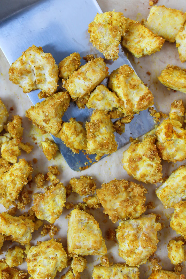 Vegan eggy tofu pieces on a baking sheet with metal spatula