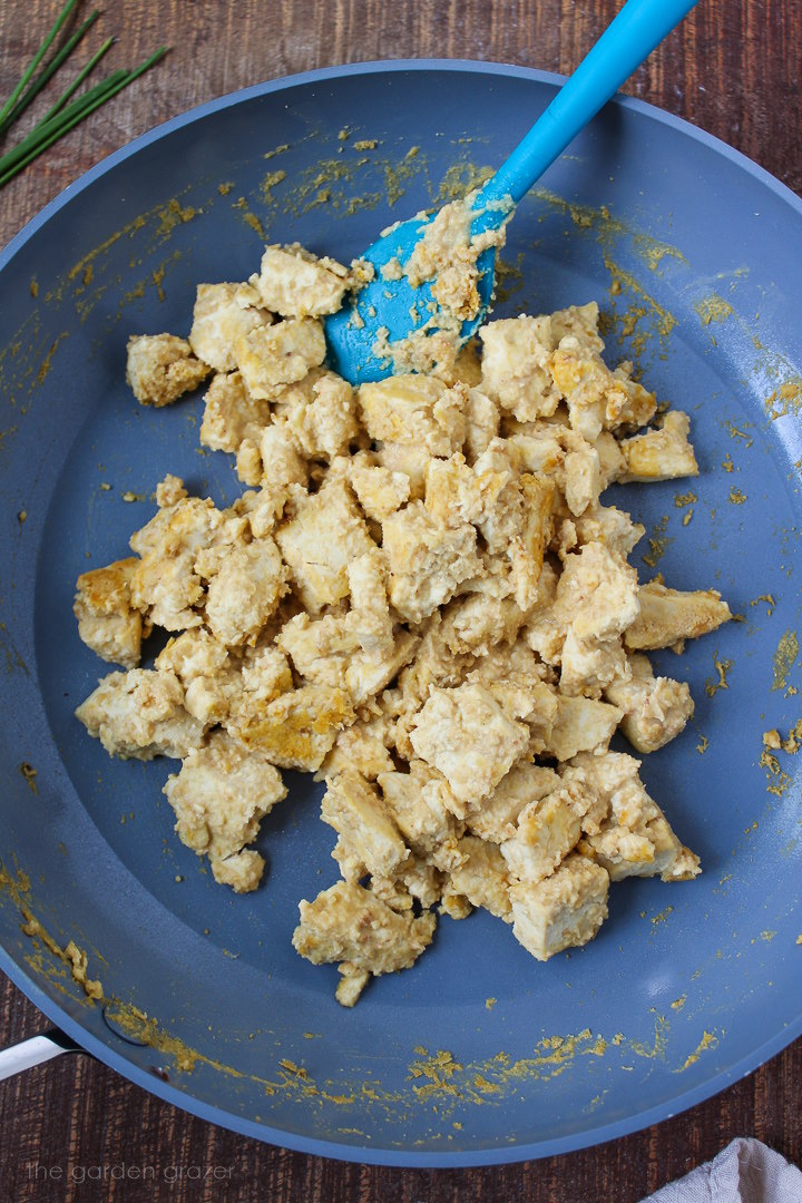 Eggy tofu cooking in a skillet with spatula