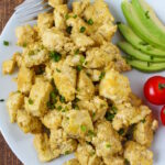 Overhead view of eggy tofu on a white plate garnished with chives