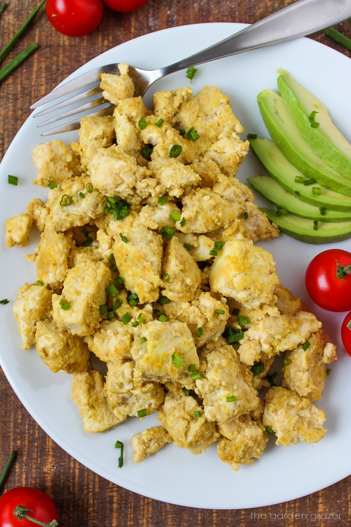 Overhead view of eggy tofu on a white plate garnished with chives