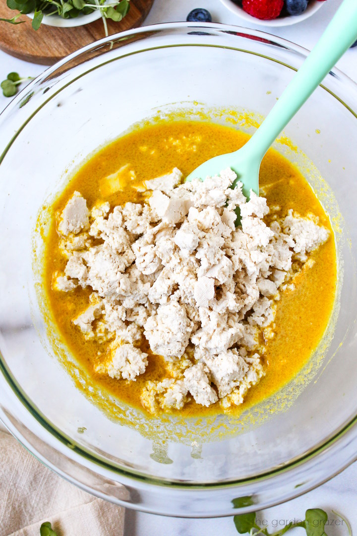 Overhead view of preparing crumbled tofu in eggy sauce before mixing together