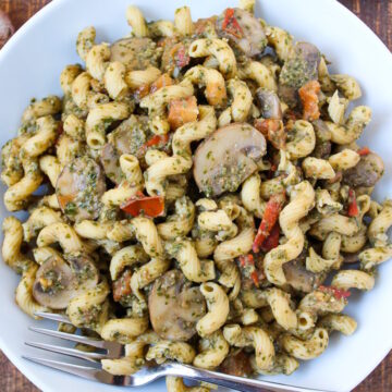 Overhead view of mushroom pesto pasta in a white bowl with serving fork