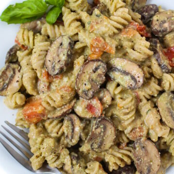 Vegan mushroom pesto pasta on a white plate with fork