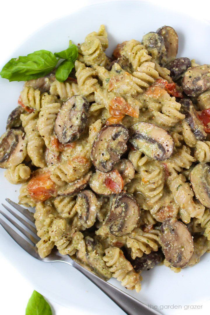 Vegan mushroom pesto pasta on a white plate with fork