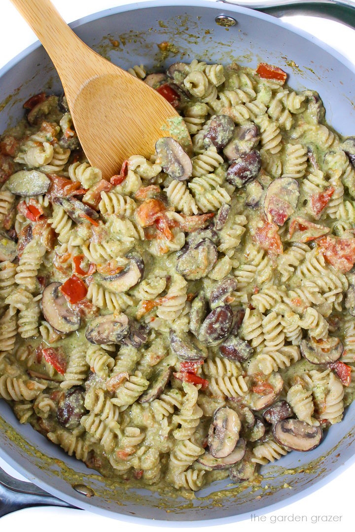 Overhead view of creamy pasta cooking in a large pan with wooden spoon