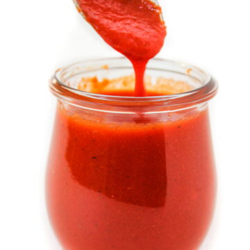 Spooning out roasted red pepper salad dressing from a glass jar