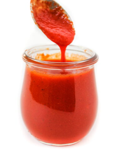 Spooning out roasted red pepper salad dressing from a glass jar