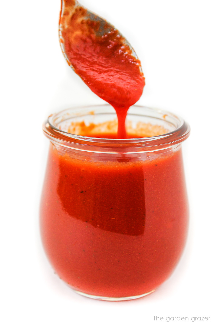 Spooning out roasted red pepper salad dressing from a glass jar