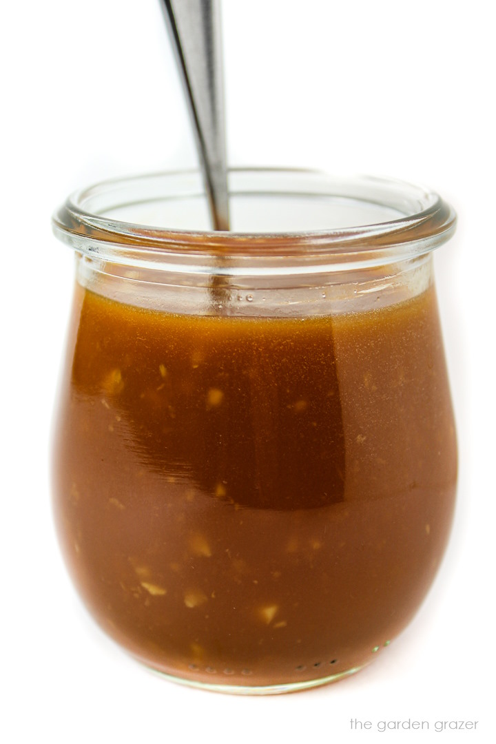 Side view of oil-free stir fry sauce in a jar with spoon