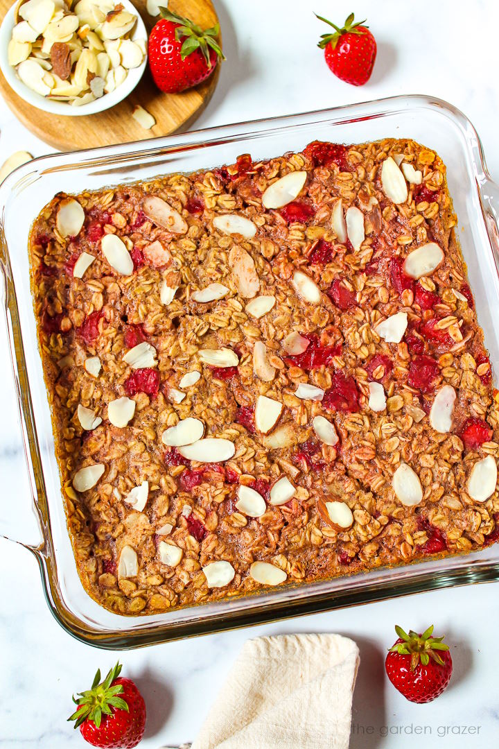 Overhead view of strawberry baked oatmeal in a glass baking dish topped with sliced almonds