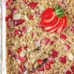 Vegan strawberry baked oatmeal in a glass baking dish with serving spoon