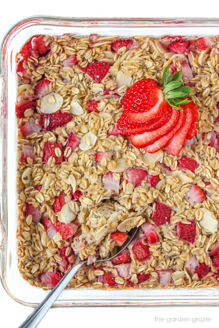 Vegan strawberry baked oatmeal in a glass baking dish with serving spoon