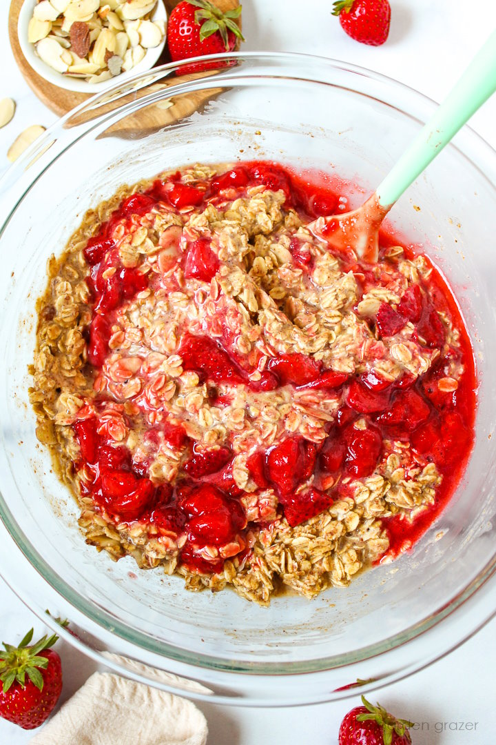 Strawberry baked oatmeal ingredients being mixed together in a glass bowl before baking