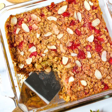 A spatula lifting strawberry baked oatmeal from a baking dish
