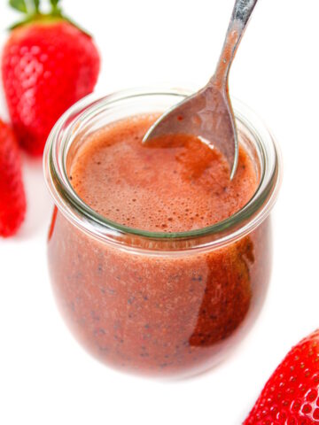 Strawberry balsamic dressing in a glass jar with serving spoon