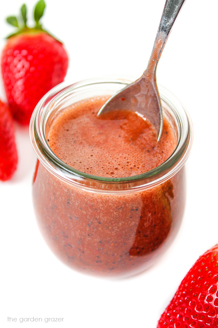 Small glass jar of strawberry balsamic dressing with metal spoon