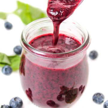Small glass jar with blueberry dressing and spoon
