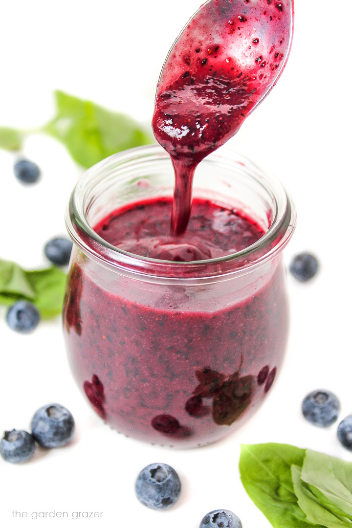 Small glass jar with blueberry dressing and spoon