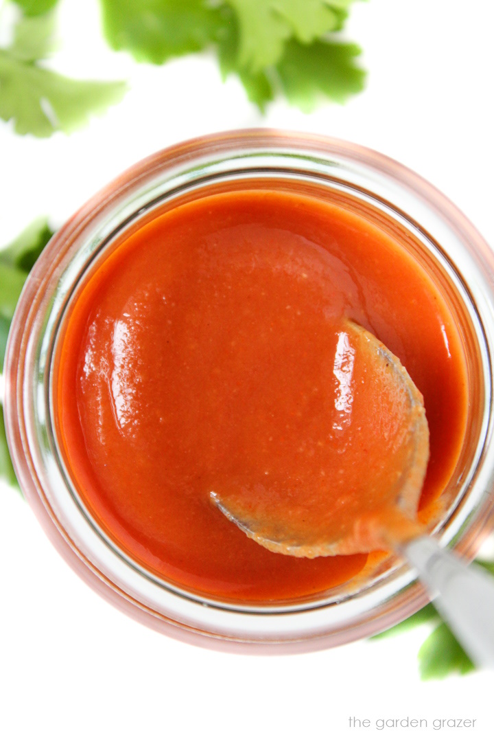 Overhead view of vegan French dressing in a glass jar with metal spoon