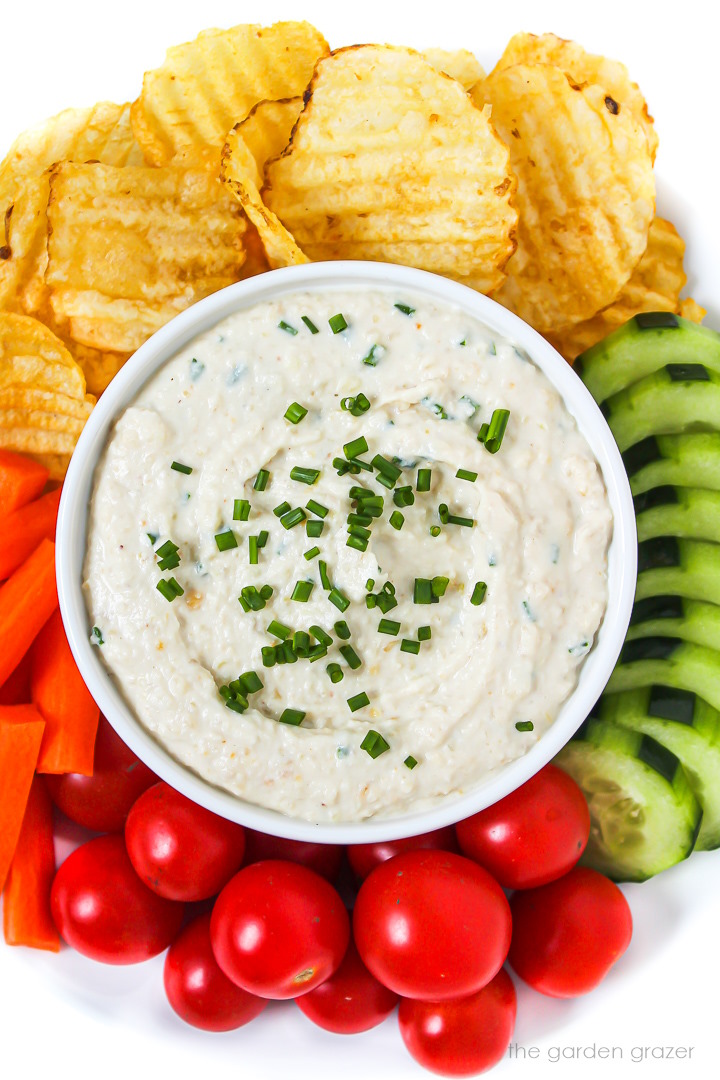 Vegan cashew French onion dip topped with chives with fresh veggies and chips