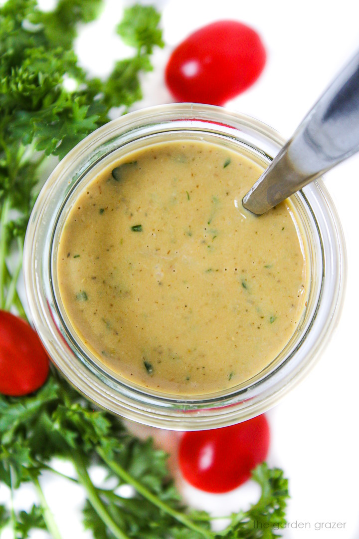 Overhead view of vegan Italian salad dressing in a glass jar with serving spoon