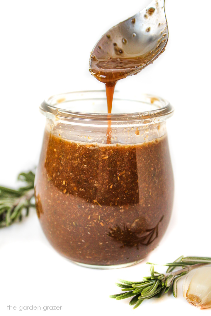 Maple balsamic dressing in a small glass jar with spoon