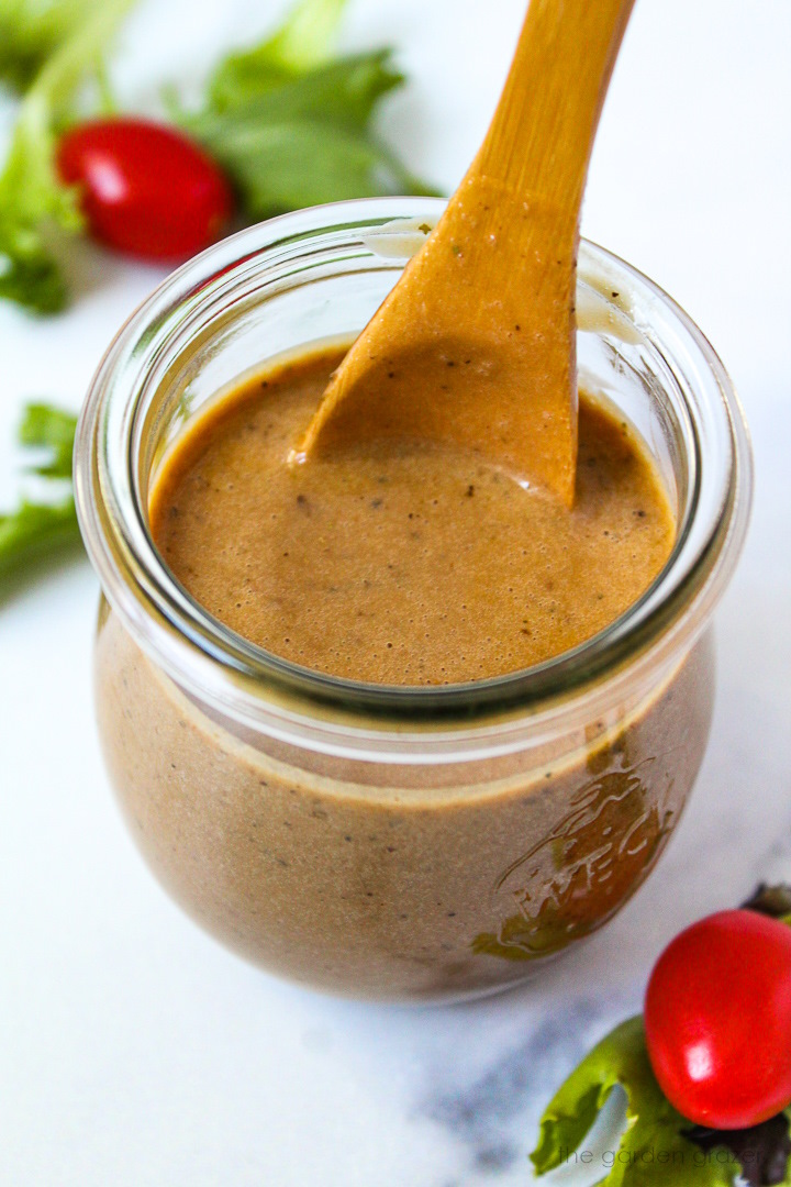 Maple balsamic dressing in a small glass jar with serving spoon